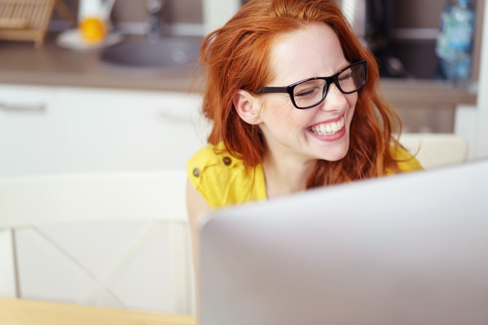 redheaded woman laughing at computer